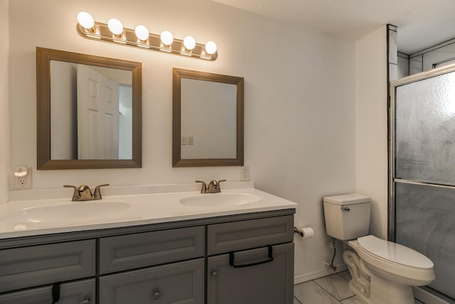 bathroom featuring a shower with door, vanity, and toilet