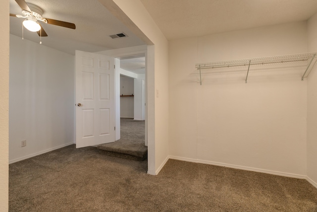 walk in closet featuring ceiling fan and dark colored carpet