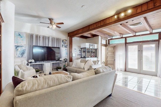 living room with beamed ceiling, light tile patterned floors, ceiling fan, and french doors