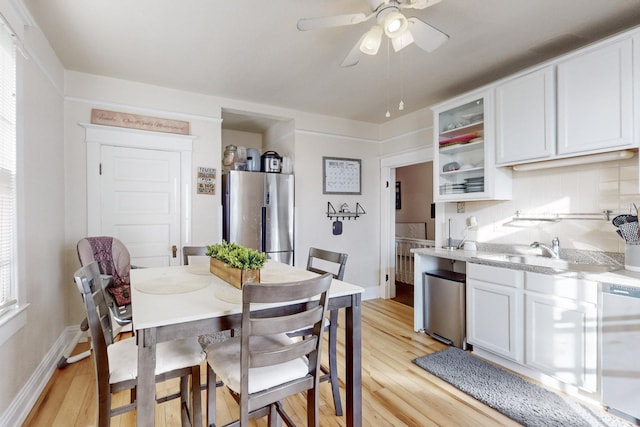 kitchen featuring stainless steel fridge, dishwasher, white cabinets, light hardwood / wood-style floors, and backsplash