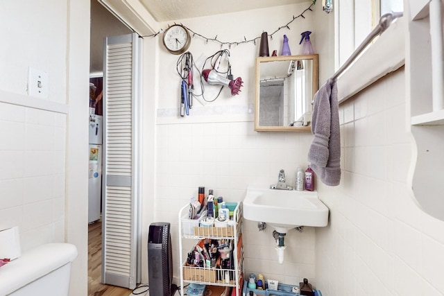 bathroom featuring toilet, sink, and tile walls