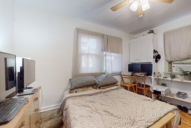 bedroom featuring ceiling fan, cooling unit, and light wood-type flooring