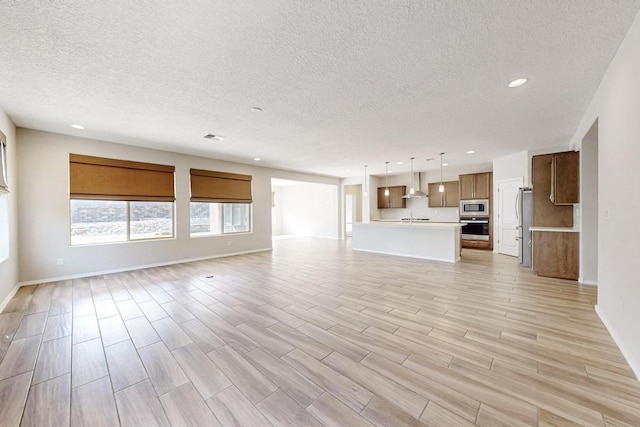 unfurnished living room featuring a textured ceiling and light wood-type flooring