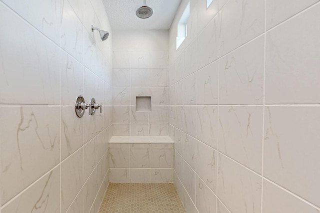 bathroom with tiled shower and a textured ceiling