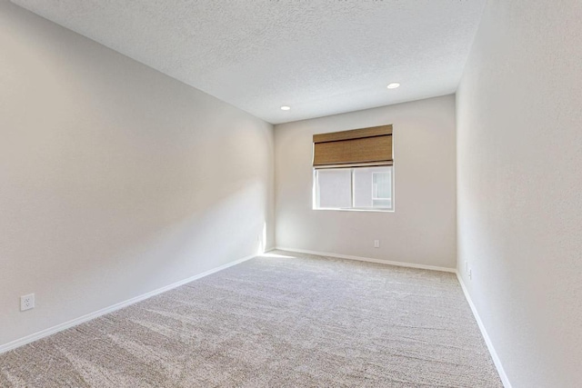 empty room with light carpet and a textured ceiling