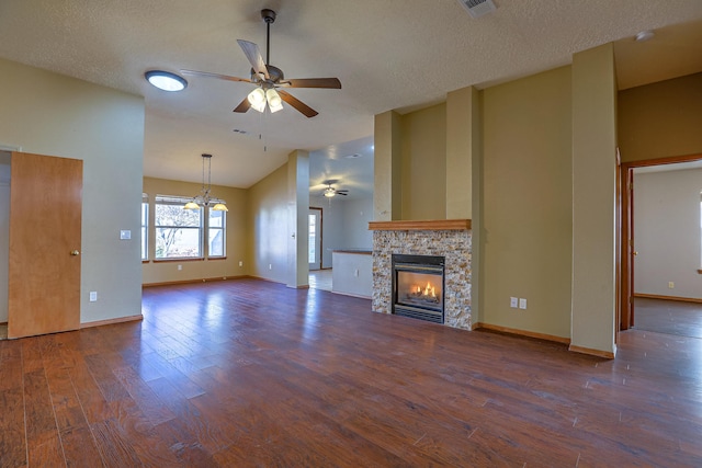 unfurnished living room featuring a stone fireplace, high vaulted ceiling, dark hardwood / wood-style flooring, ceiling fan, and a textured ceiling