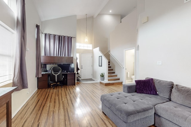 living room with hardwood / wood-style flooring, built in desk, and high vaulted ceiling