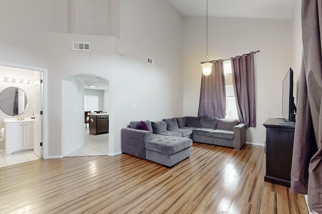 living room featuring high vaulted ceiling and light hardwood / wood-style floors