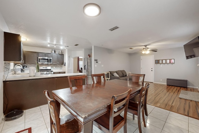 dining space featuring ceiling fan, sink, and light tile patterned floors