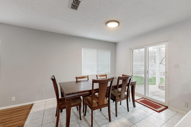 tiled dining room featuring a textured ceiling