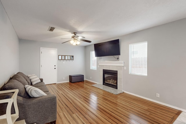 living room with ceiling fan, a fireplace, and light wood-type flooring