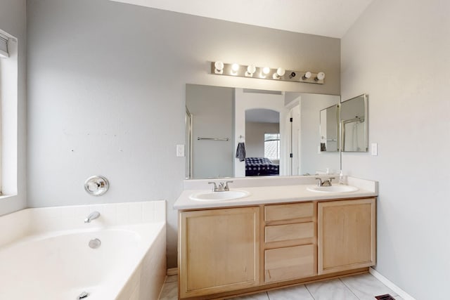 bathroom with vanity and tiled bath