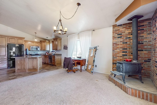 kitchen featuring vaulted ceiling, a kitchen island, appliances with stainless steel finishes, decorative light fixtures, and a wood stove