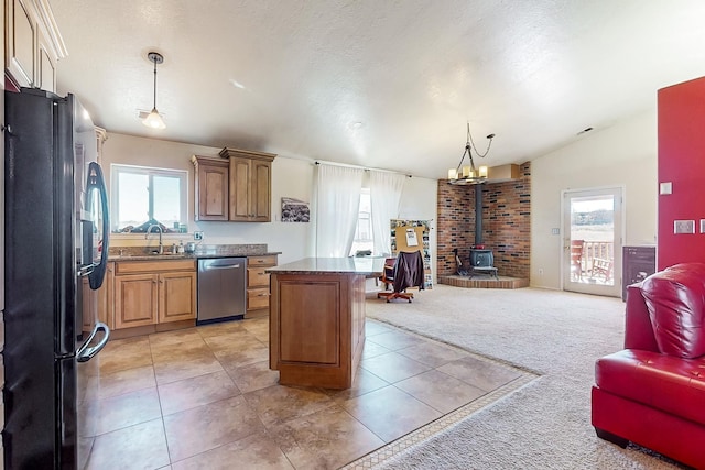 kitchen with black refrigerator, decorative light fixtures, dishwasher, sink, and a wood stove