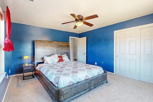 carpeted bedroom featuring ceiling fan, a closet, and a textured ceiling