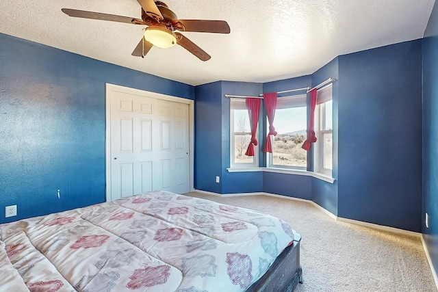 bedroom with ceiling fan, carpet, and a textured ceiling