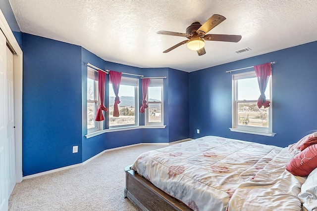 bedroom featuring carpet flooring, a textured ceiling, ceiling fan, and a closet