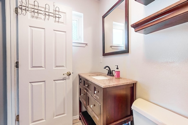 bathroom featuring vanity, plenty of natural light, and toilet