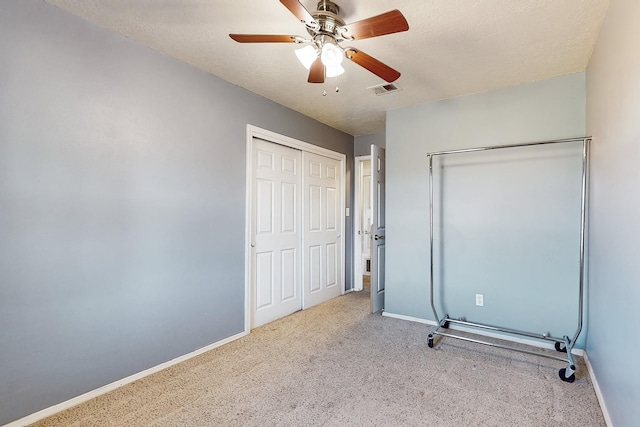 unfurnished bedroom with ceiling fan, light carpet, and a textured ceiling