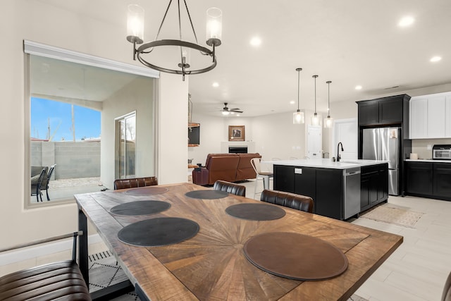 dining room with sink and ceiling fan with notable chandelier