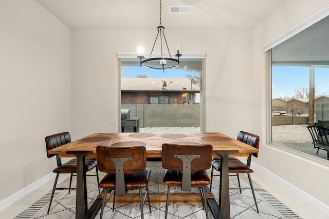 tiled dining space featuring a notable chandelier and a wealth of natural light