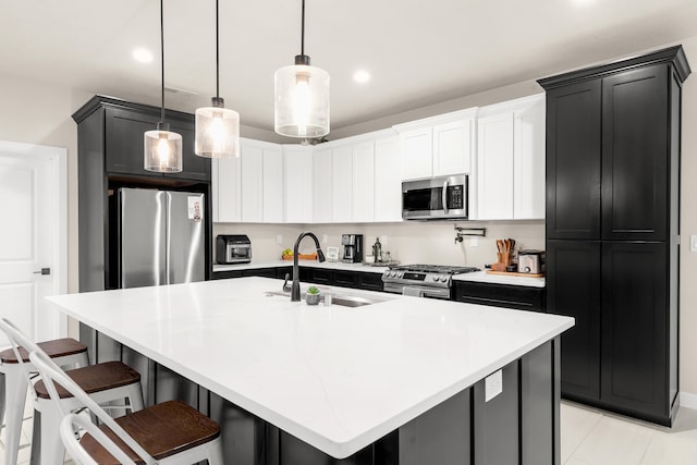 kitchen featuring sink, hanging light fixtures, a kitchen breakfast bar, an island with sink, and stainless steel appliances