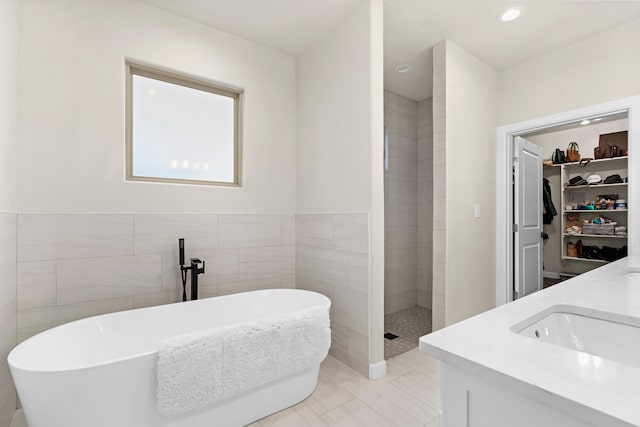 bathroom with vanity, independent shower and bath, tile patterned flooring, and tile walls