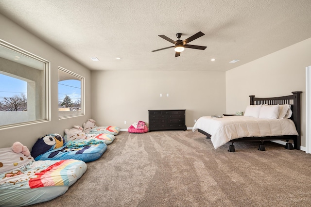 bedroom with ceiling fan, carpet floors, and a textured ceiling