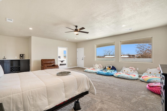 bedroom with ceiling fan, carpet floors, and a textured ceiling