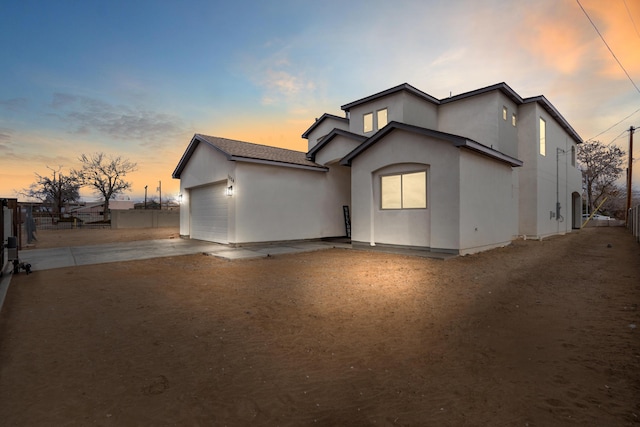 back house at dusk featuring a garage