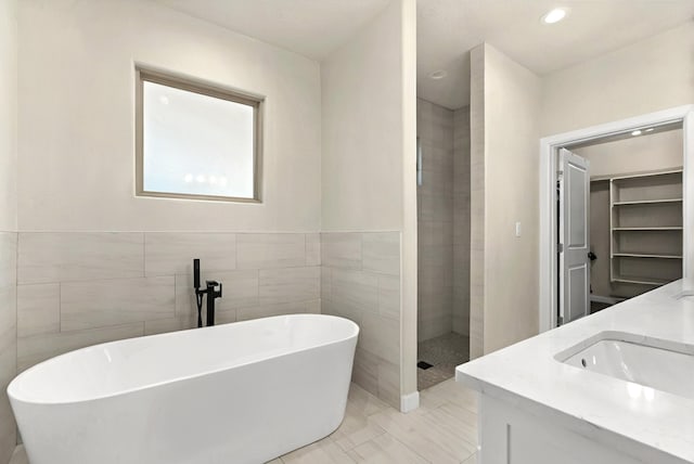 bathroom featuring vanity, tile walls, and plus walk in shower