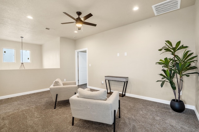 sitting room with ceiling fan, dark carpet, and a textured ceiling