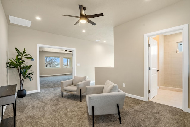 living area featuring light carpet and ceiling fan