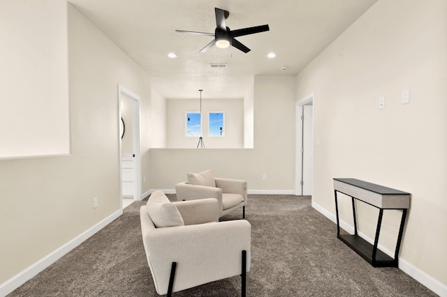 living area with ceiling fan and dark colored carpet