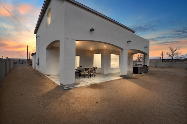 back house at dusk featuring a patio area