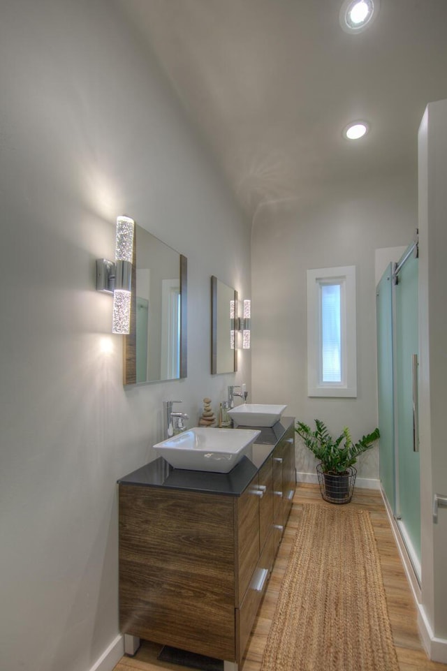 bathroom featuring wood-type flooring, a shower with door, and vanity