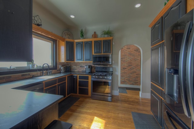 kitchen featuring decorative backsplash, stainless steel appliances, sink, and light hardwood / wood-style flooring