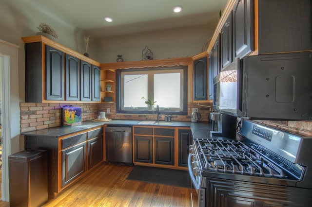 kitchen featuring appliances with stainless steel finishes, sink, decorative backsplash, light hardwood / wood-style floors, and dark brown cabinets