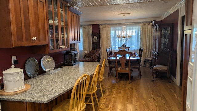 dining space featuring crown molding, light hardwood / wood-style flooring, a chandelier, and a textured ceiling