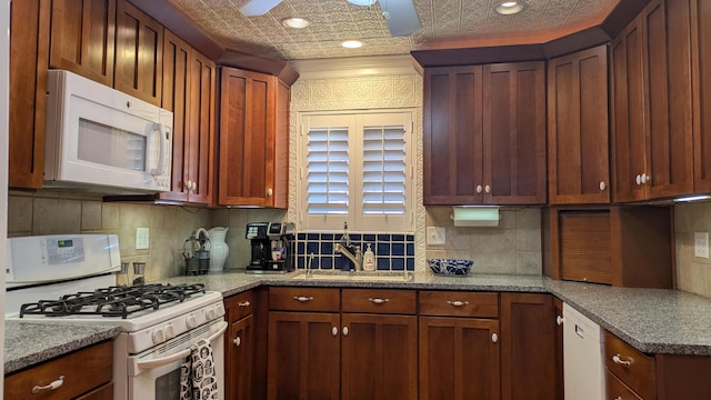 kitchen with white appliances, ornamental molding, decorative backsplash, and dark stone countertops