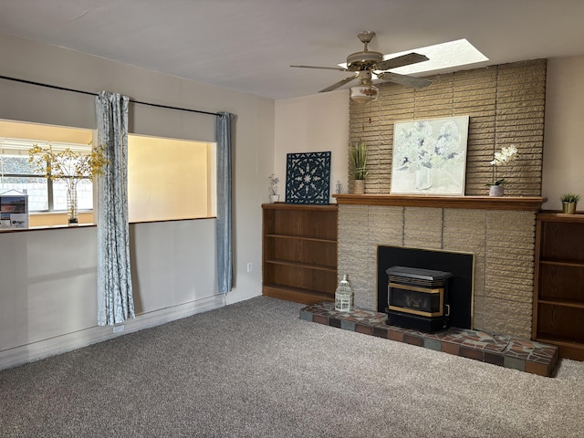 living room with a wood stove, carpet, and ceiling fan