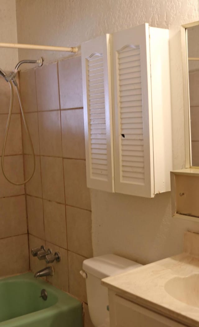 full bathroom featuring vanity, tiled shower / bath, and toilet