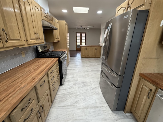 kitchen featuring tasteful backsplash, a skylight, stainless steel appliances, and butcher block counters