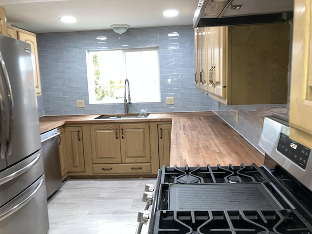 kitchen featuring sink, extractor fan, tasteful backsplash, wooden counters, and appliances with stainless steel finishes