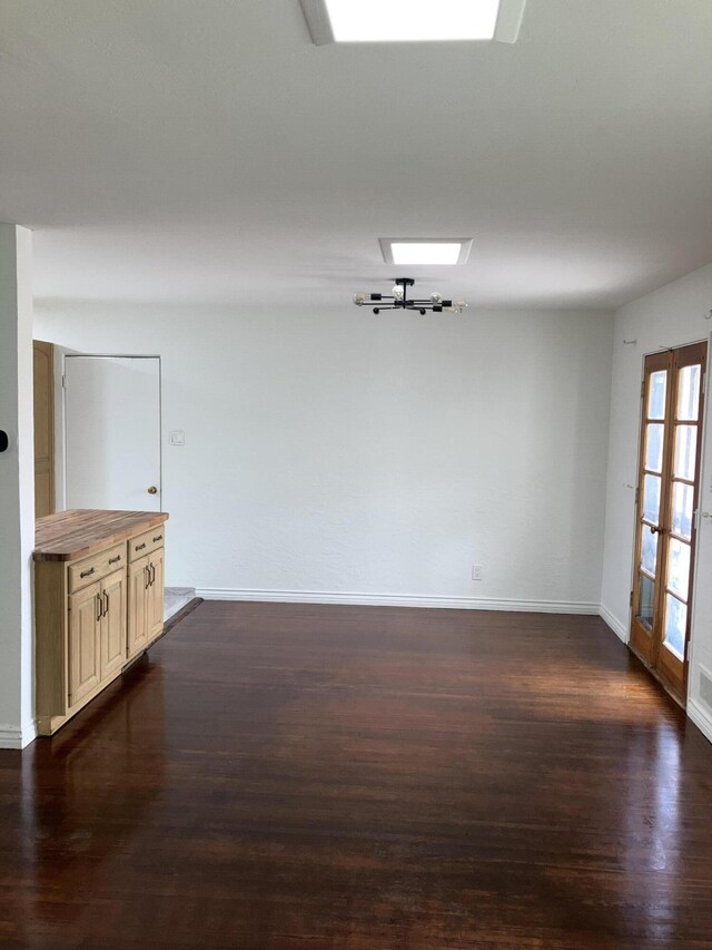 empty room with a skylight, dark wood-type flooring, and french doors