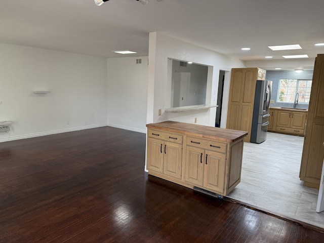 kitchen featuring sink, hardwood / wood-style flooring, stainless steel fridge, a skylight, and kitchen peninsula