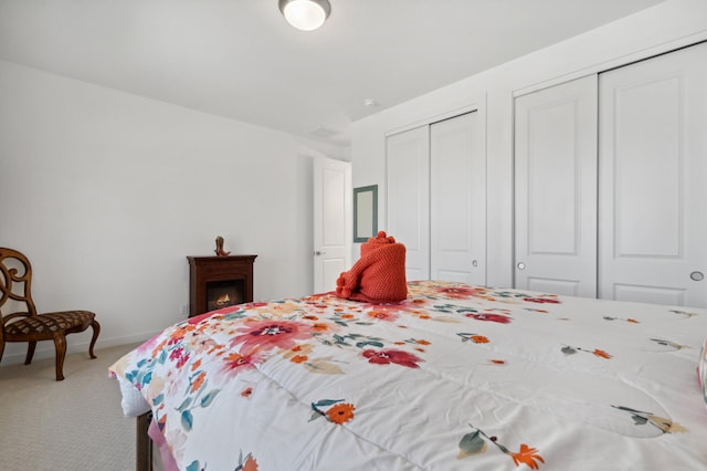 bedroom with multiple closets and carpet flooring