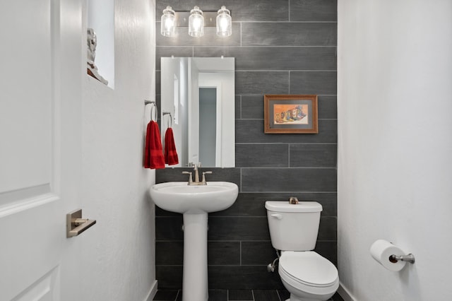 bathroom with tile walls, sink, and toilet