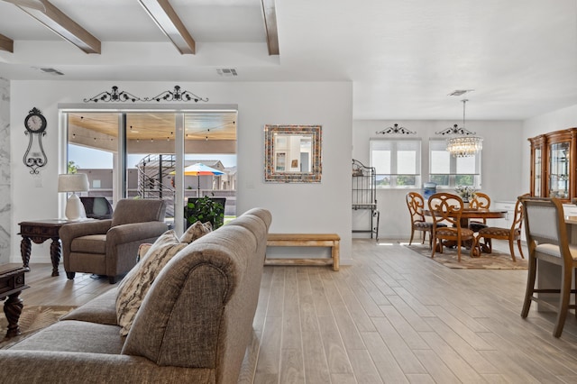 living room featuring an inviting chandelier, beam ceiling, and light hardwood / wood-style floors