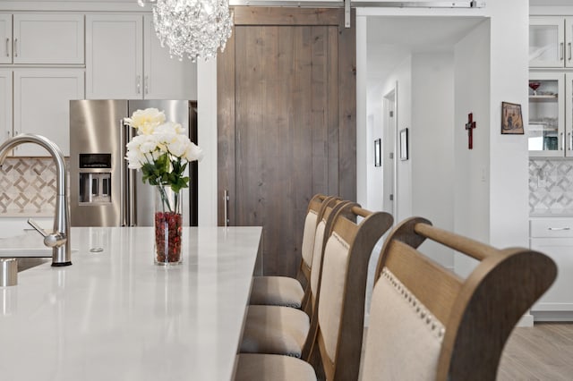 dining area with sink, a notable chandelier, a barn door, and light wood-type flooring